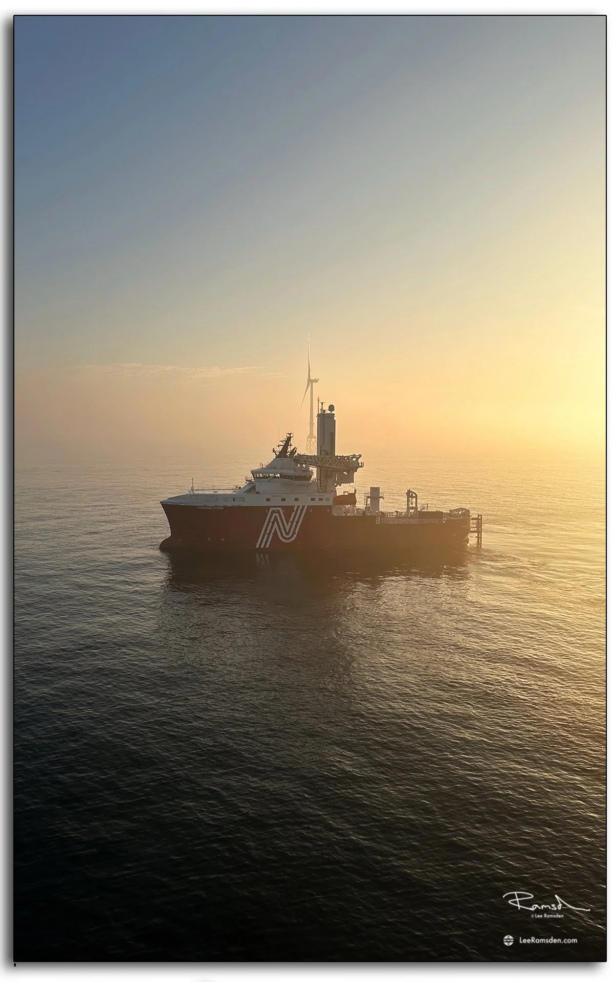Norwind Storm vessel at sunrise with wind turbines on the horizon, captured in the North Sea