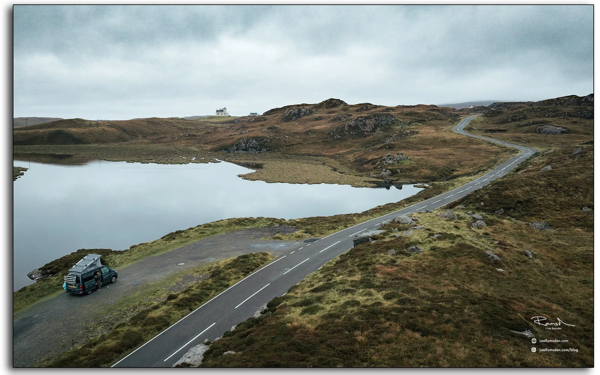 Winding single-track road near Uig Lodge on the Isle of Lewis, Outer Hebrides, with calm loch reflections and a campervan parked at the roadside