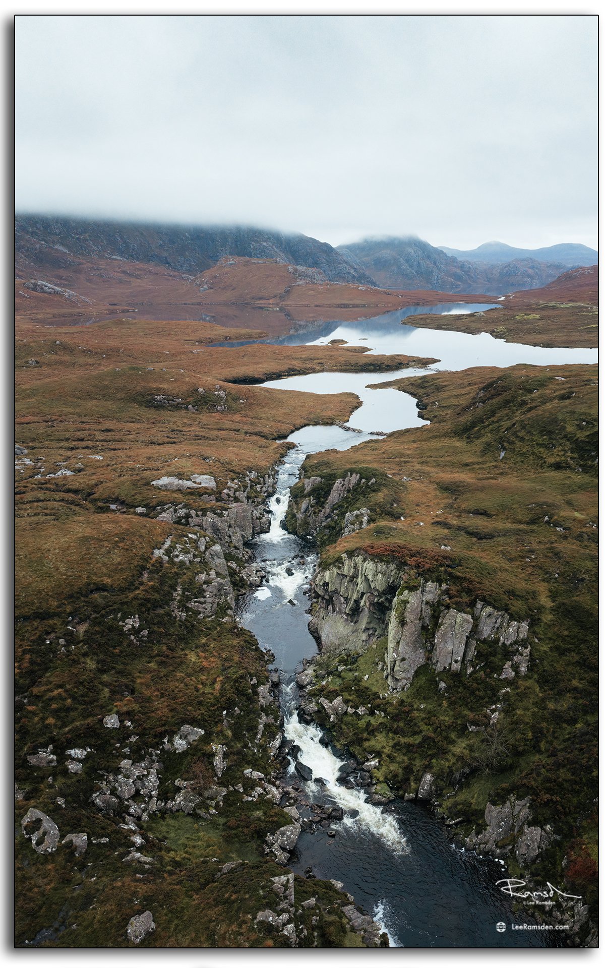 Winding single-track road near Uig Lodge on the Isle of Lewis, Outer Hebrides, with calm loch reflections