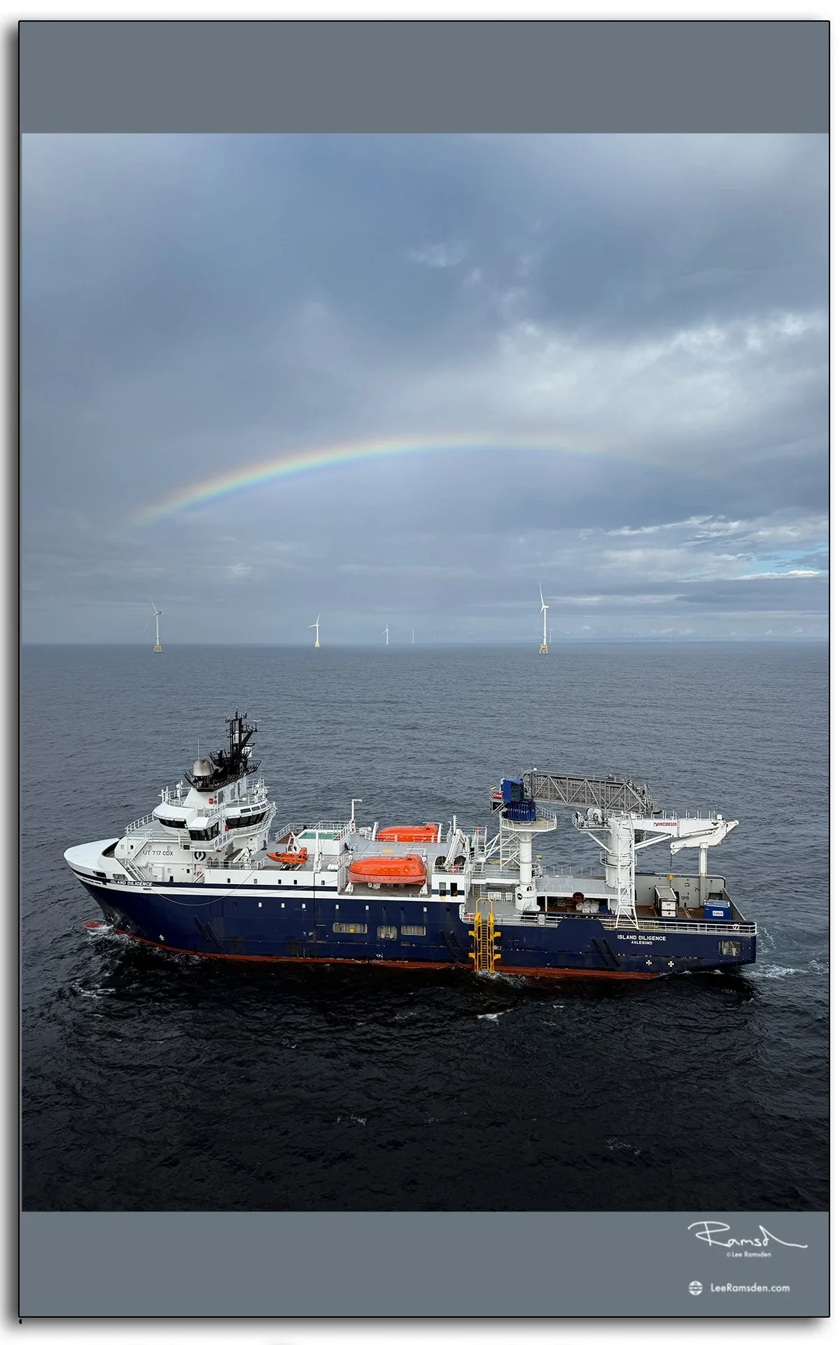 Service operation vessel Island Diligence under a rainbow at a Scottish offshore wind farm. Industrial and maritime photography.