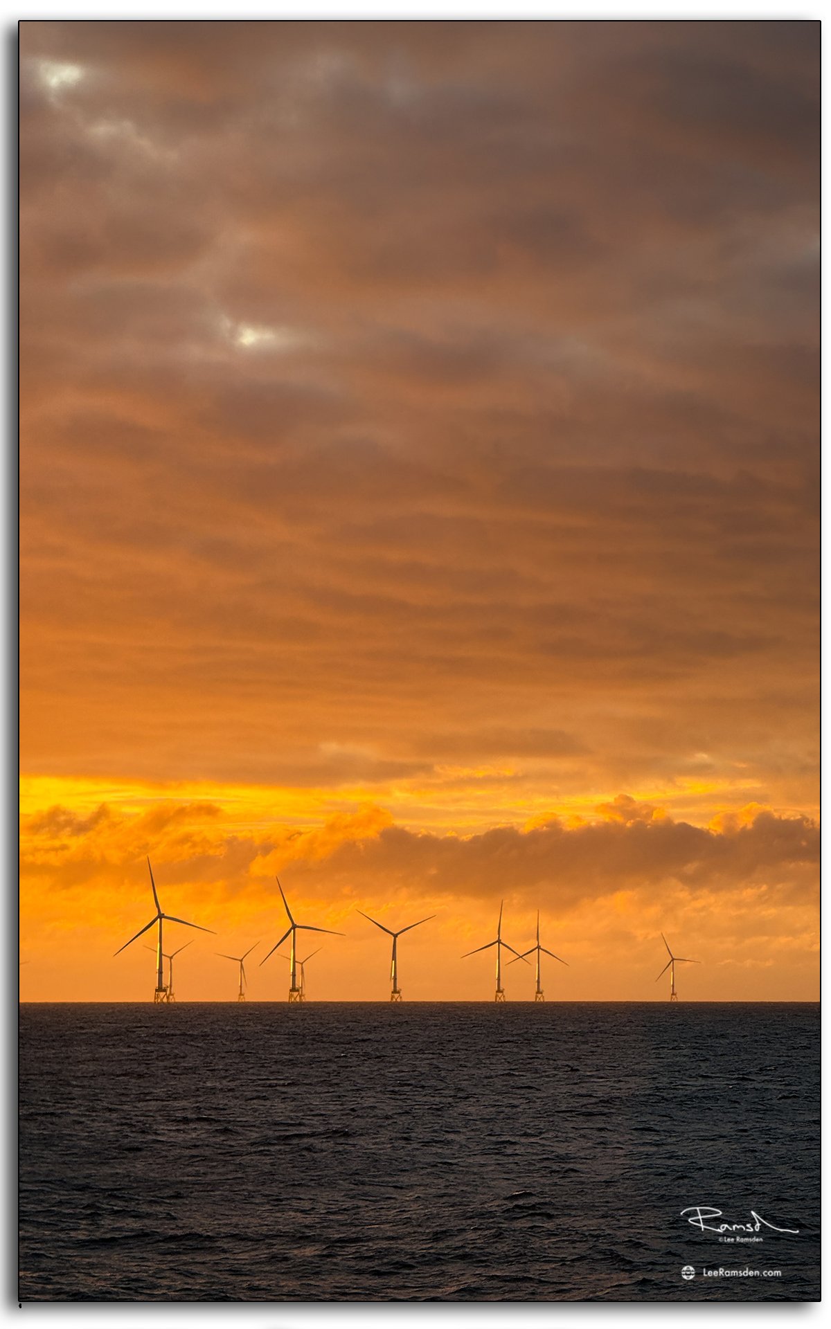 Turbines silhouetted against fiery orange evening skies.
