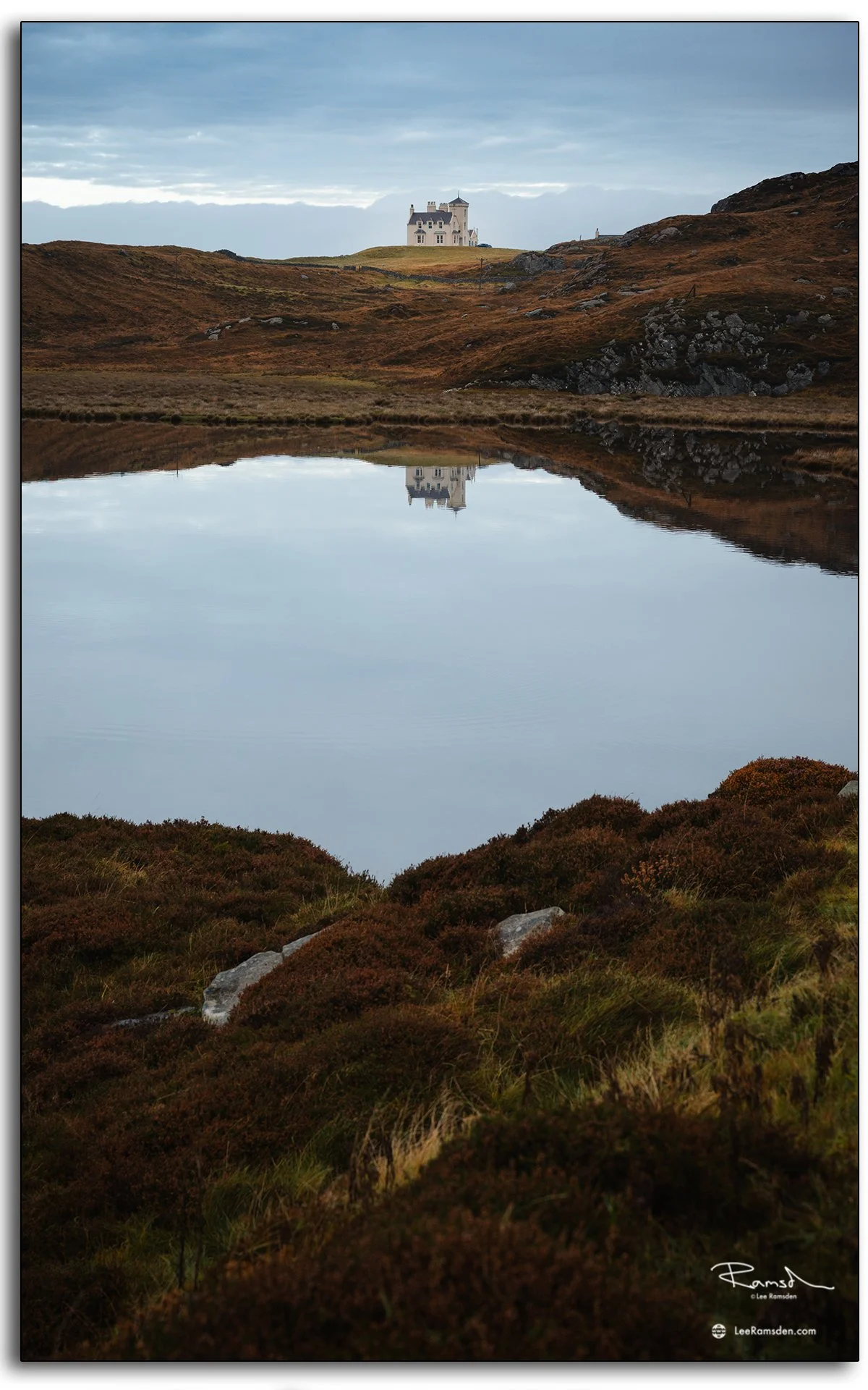 Winding single-track road near Uig Lodge on the Isle of Lewis, Outer Hebrides, with calm loch reflections