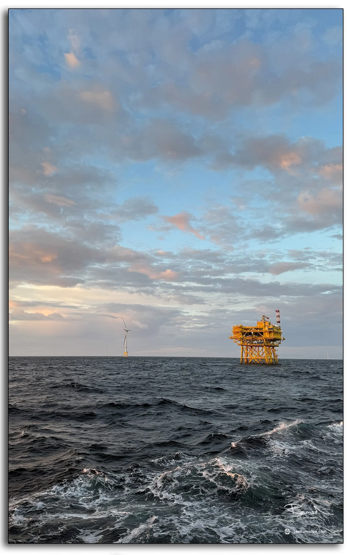 Offshore wind turbine and substation platform in golden evening light, North Sea.