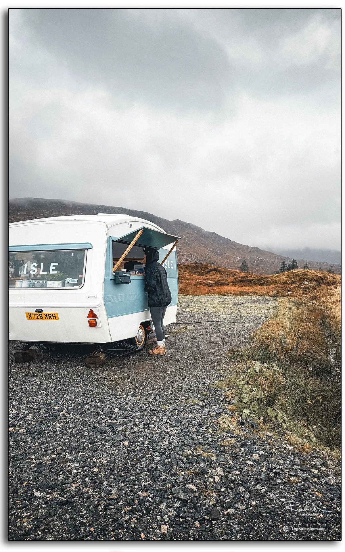 Two takeaway coffees held up in front of the Isle Coffee van on the Isle of Harris, Scotland, during a rainy Hebridean morning.