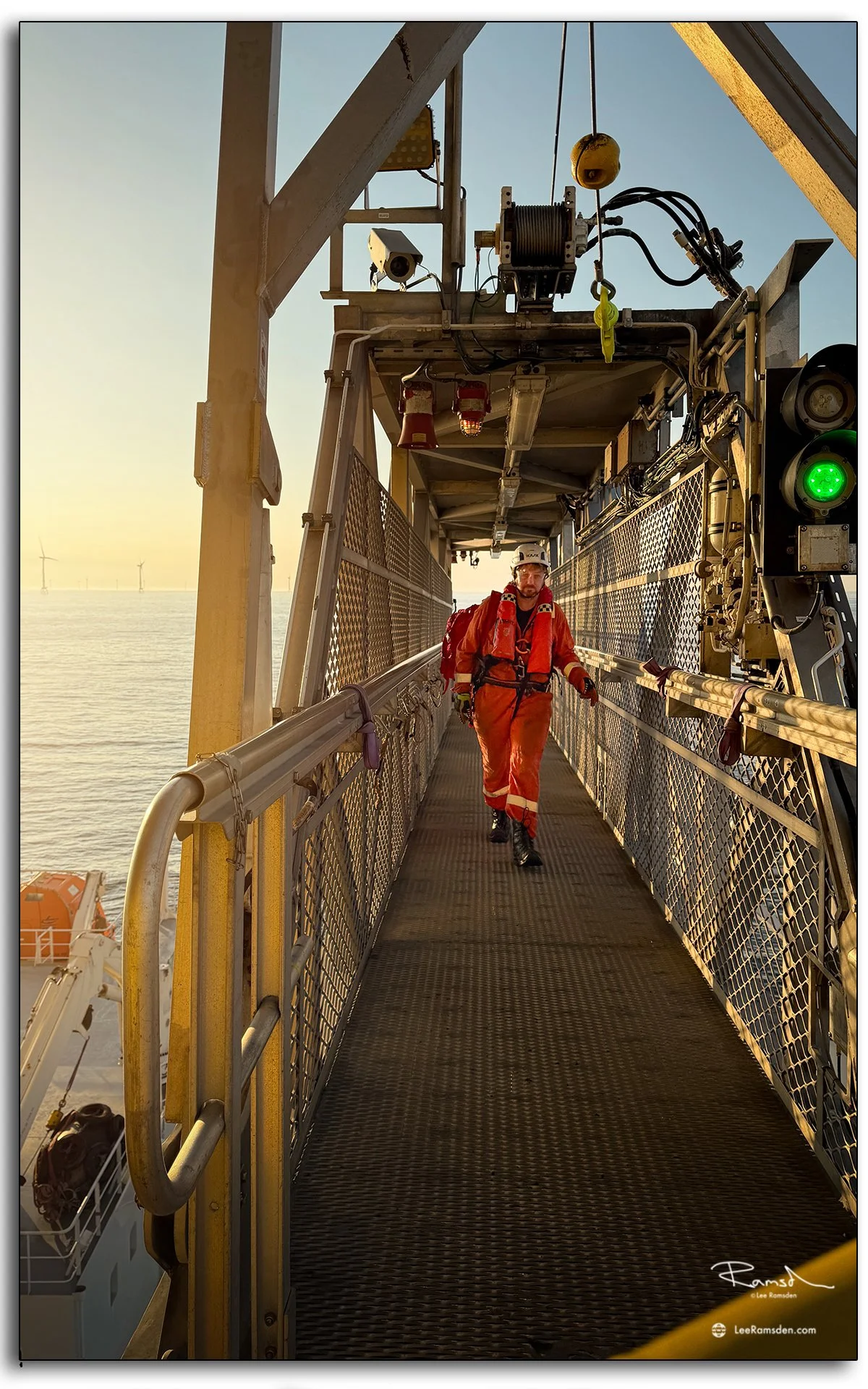 Offshore worker crossing Walk-to-Work bridge at sunrise, safe access between vessel and platform.