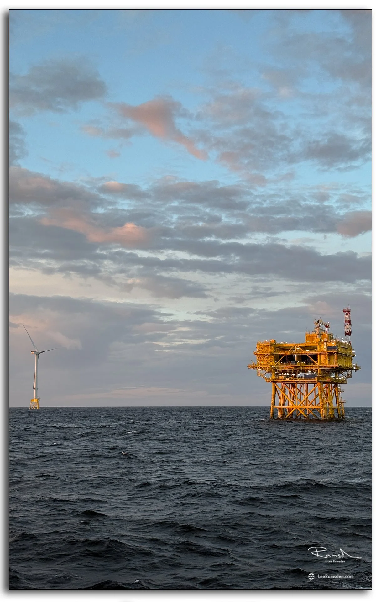 Offshore wind turbine and substation platform in golden evening light, North Sea.