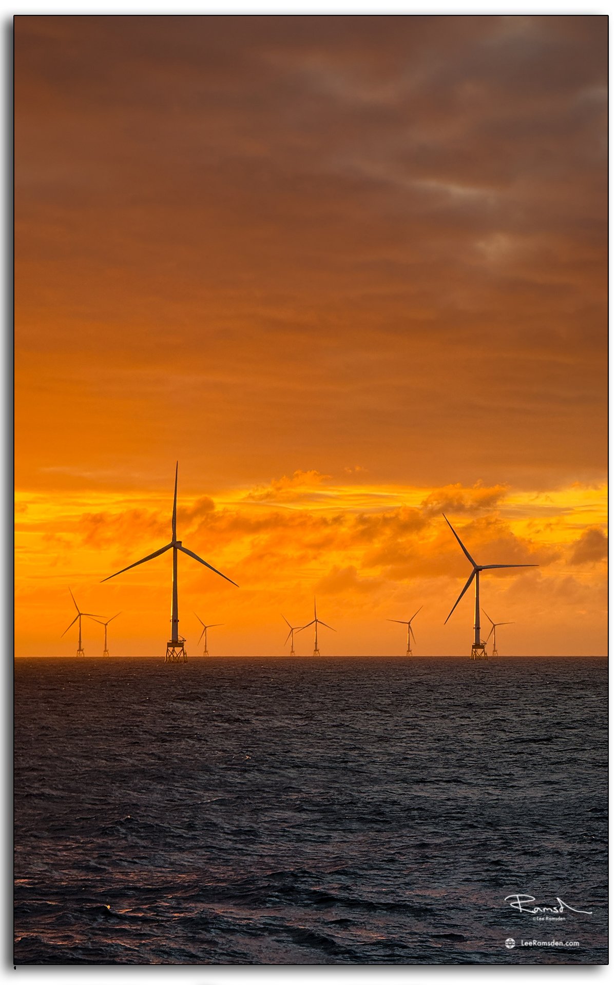 Dramatic sunset sky over North Sea wind turbines.