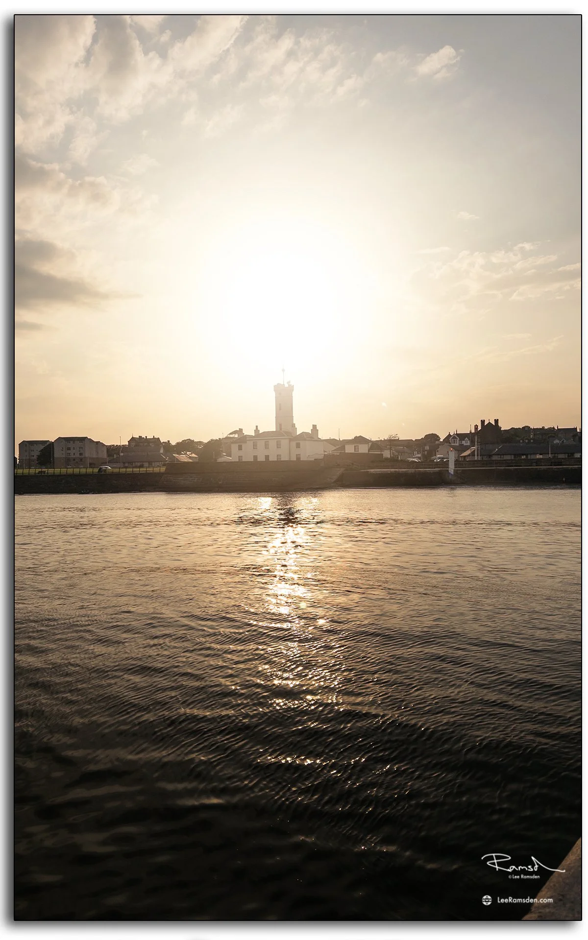Golden light at Arbroath Harbour with the lighthouse on the horizon.