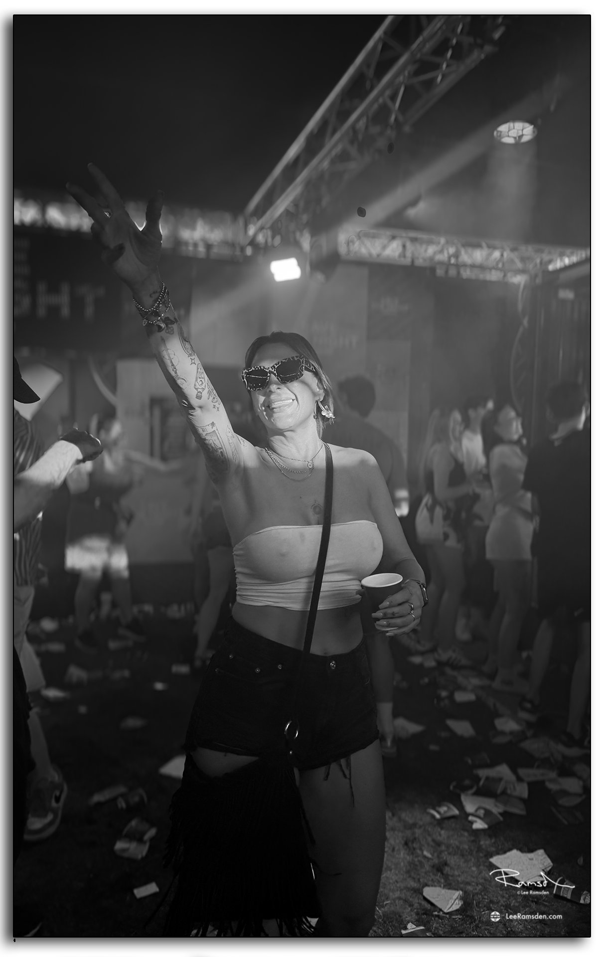 Festival-goer dancing with drink in hand at TRNSMT Festival under stage lighting.