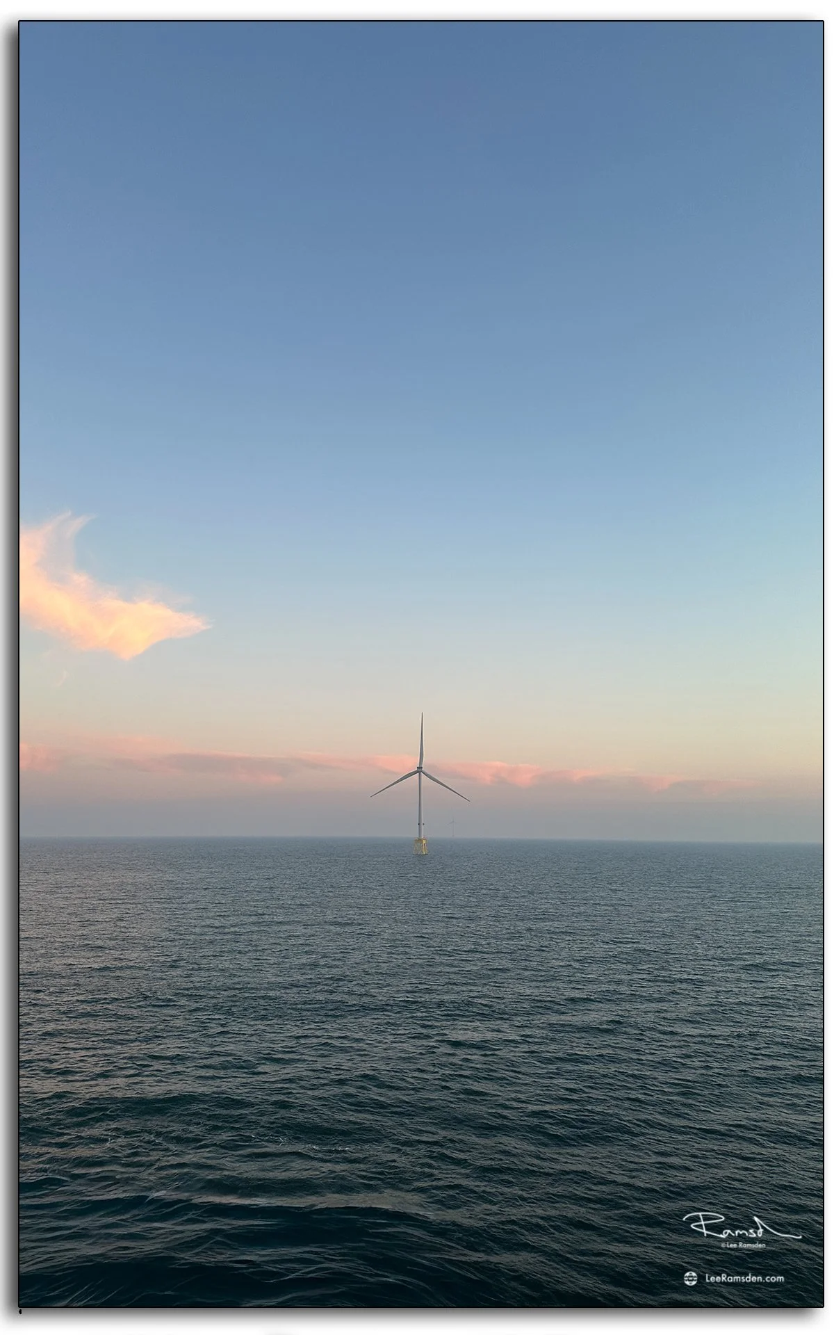 Single turbine standing against a fading pink and blue horizon, capturing the quiet beauty of offshore energy.
