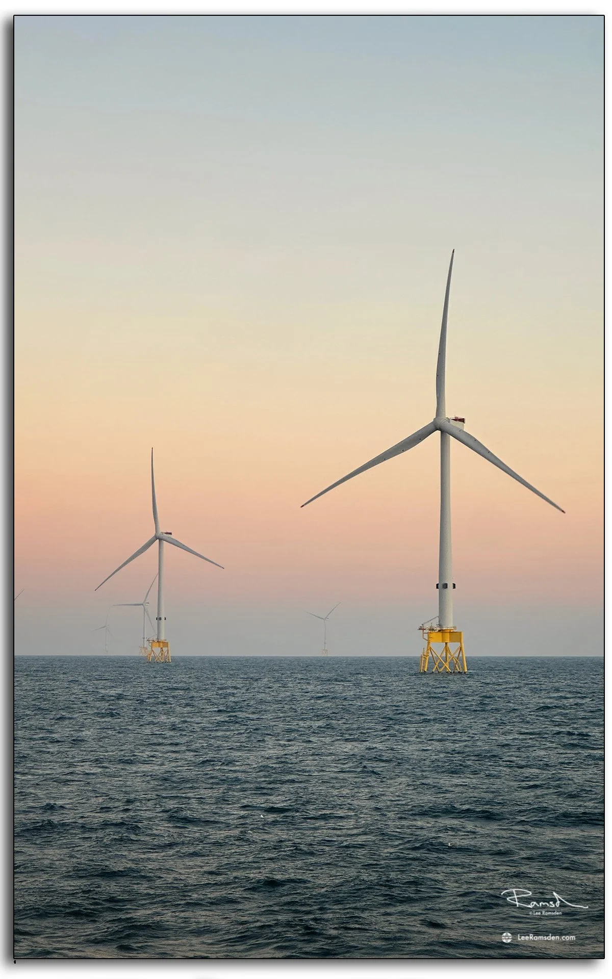 wo offshore wind turbines in soft evening light, reflecting the strength of renewables on the open sea.