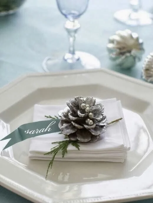 A spray-painted pinecone and a sprig of conifer makes a beautiful place setting.