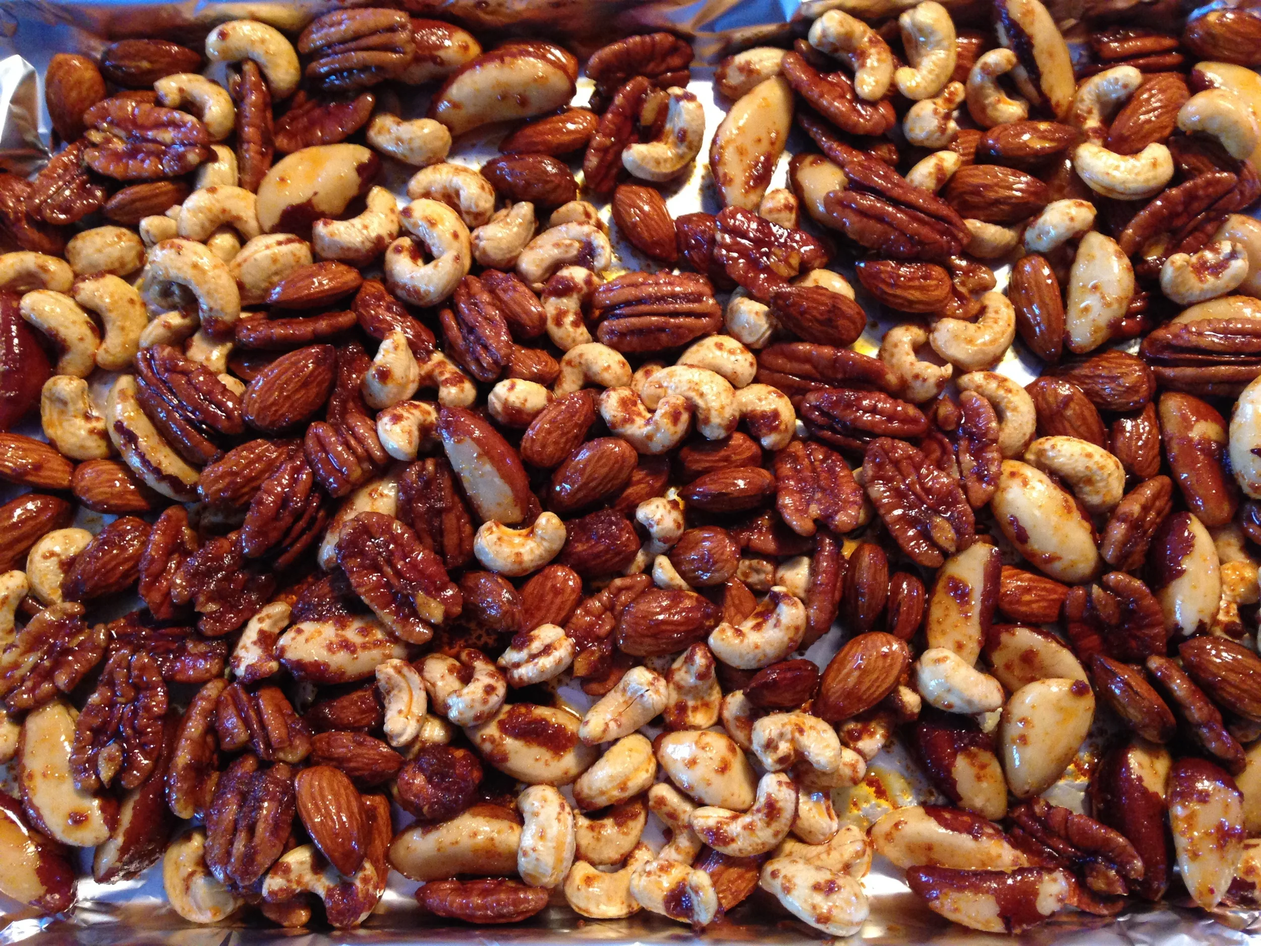 Coated nuts spread on the tray for cooking.