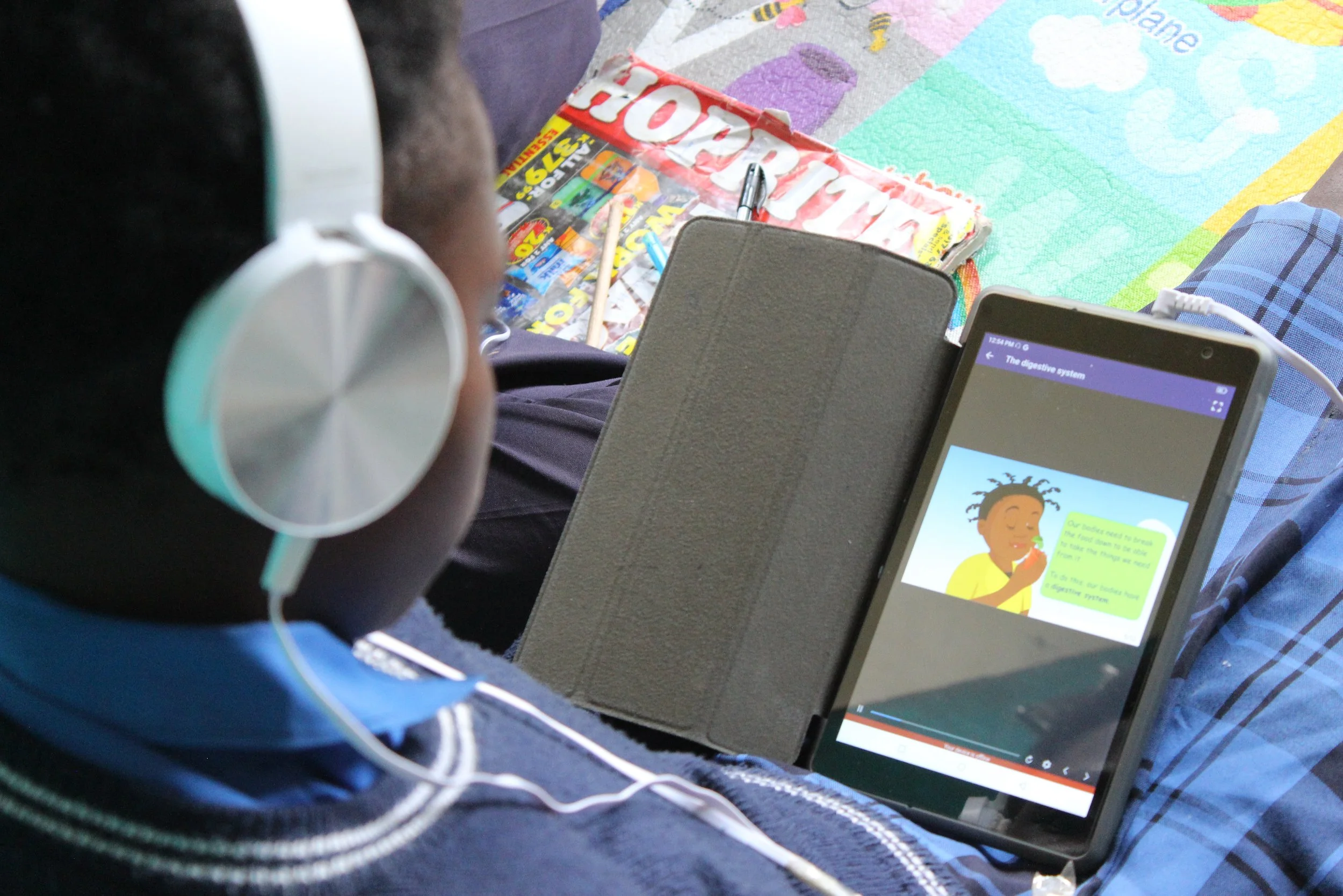 Picture of a Zambian student wearing headphones while working on a tablet computer.