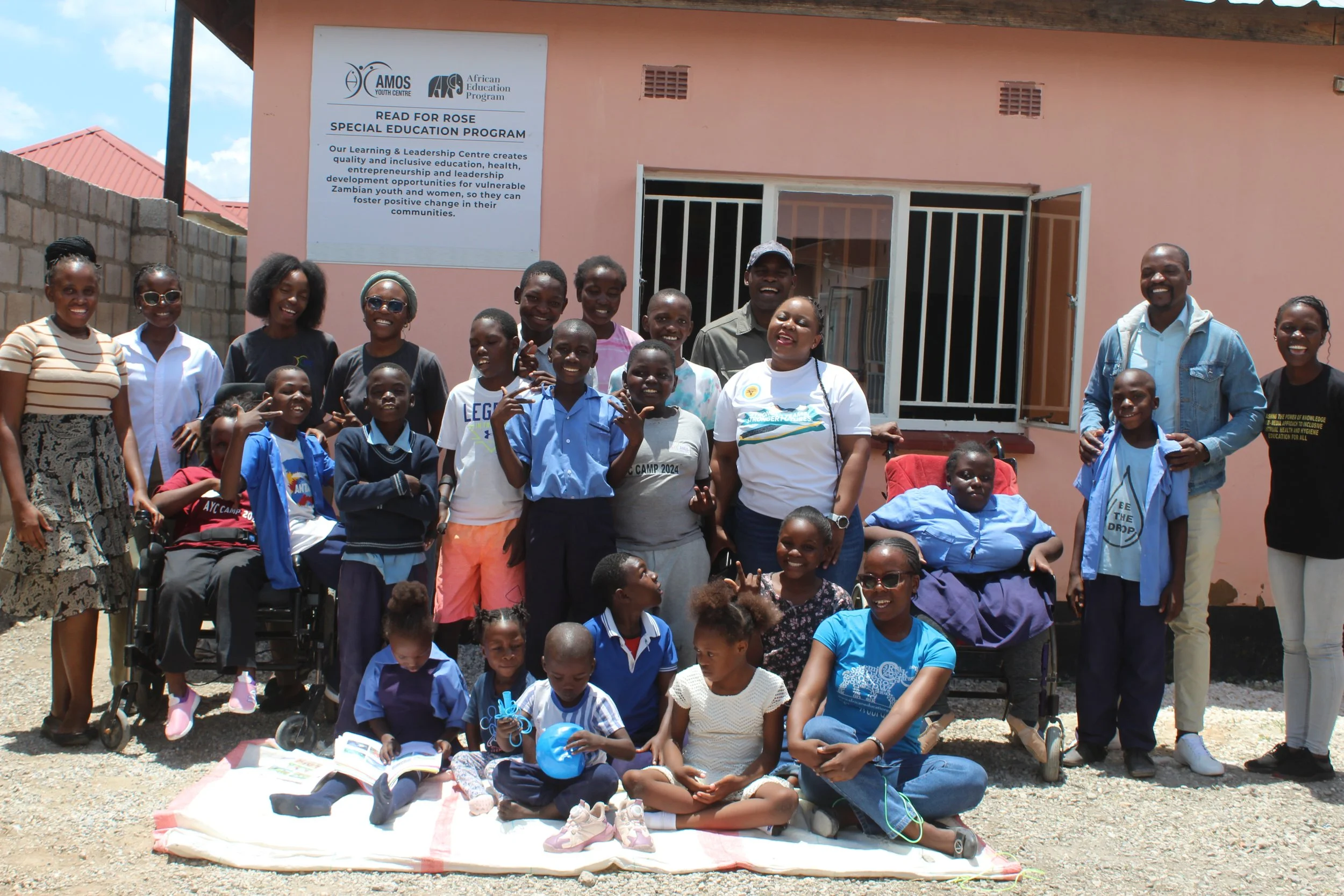 A group of students in the Read for Rose Special Education Program pose in front of their building and smile for the camera.