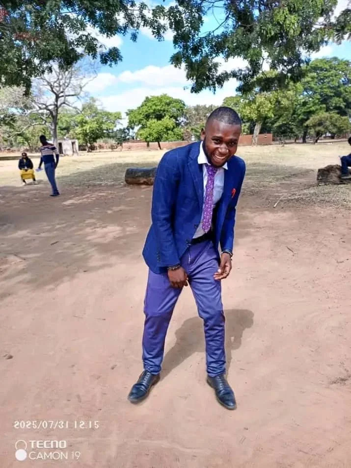 A Zambian man wearing a blue suit smiles for the camera.
