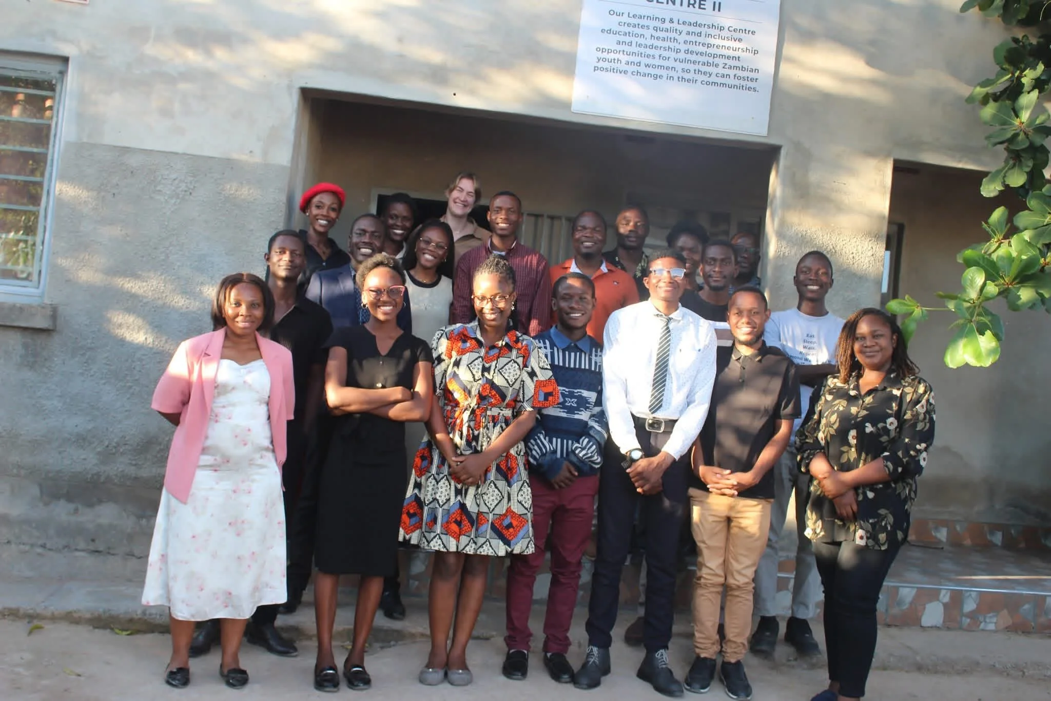 The staff at the Amos Youth Centre stand in front of a grey cinderblock building, smiling for the camera.