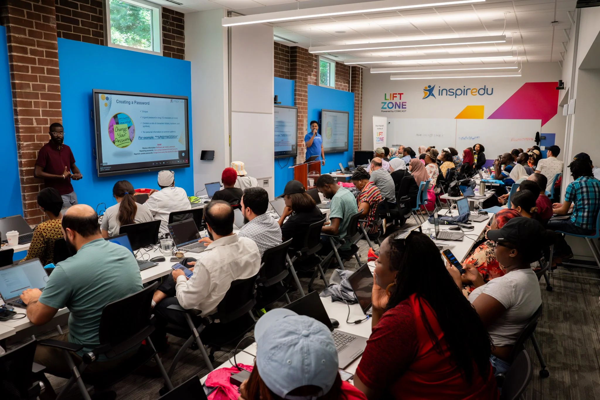 Community members participating in an Inspiredu digital skills workshop using laptops.
