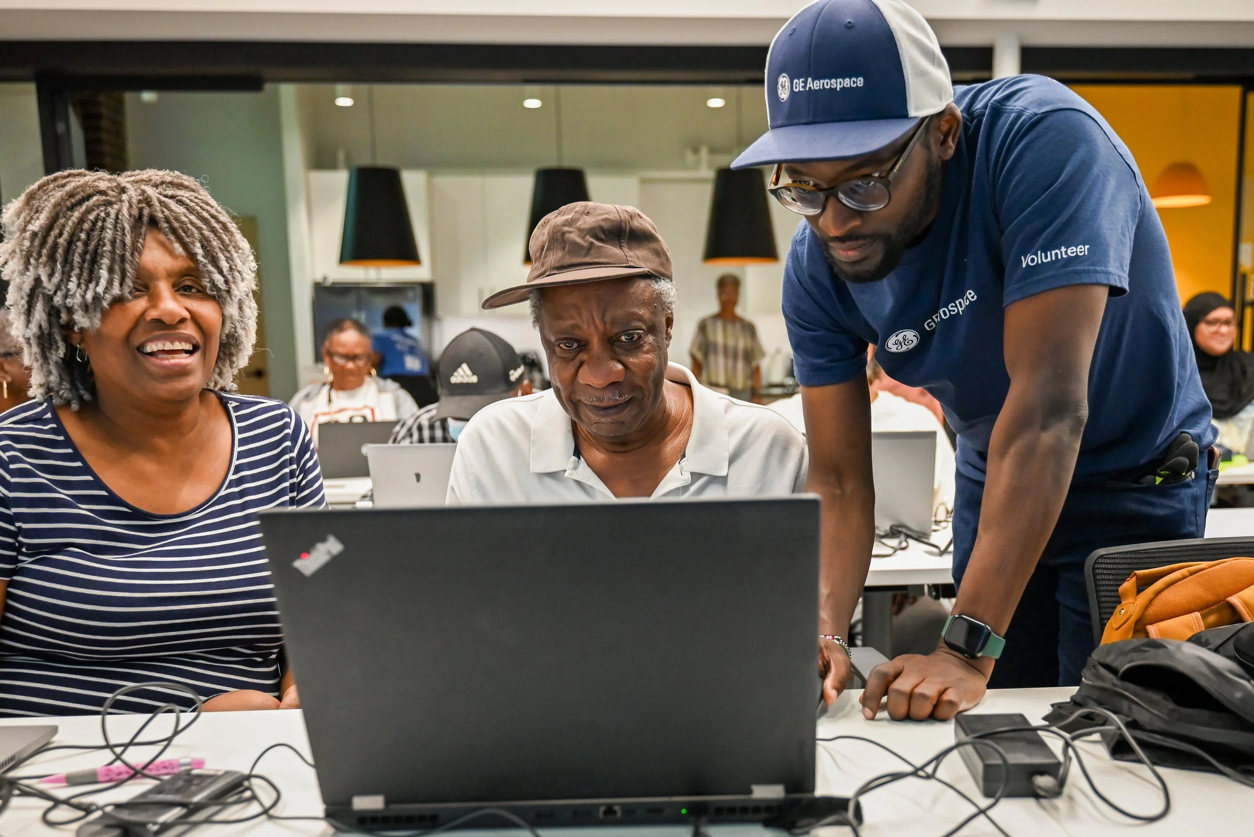 Inspiredu volunteer assisting adult learners with digital skills on a laptop.
