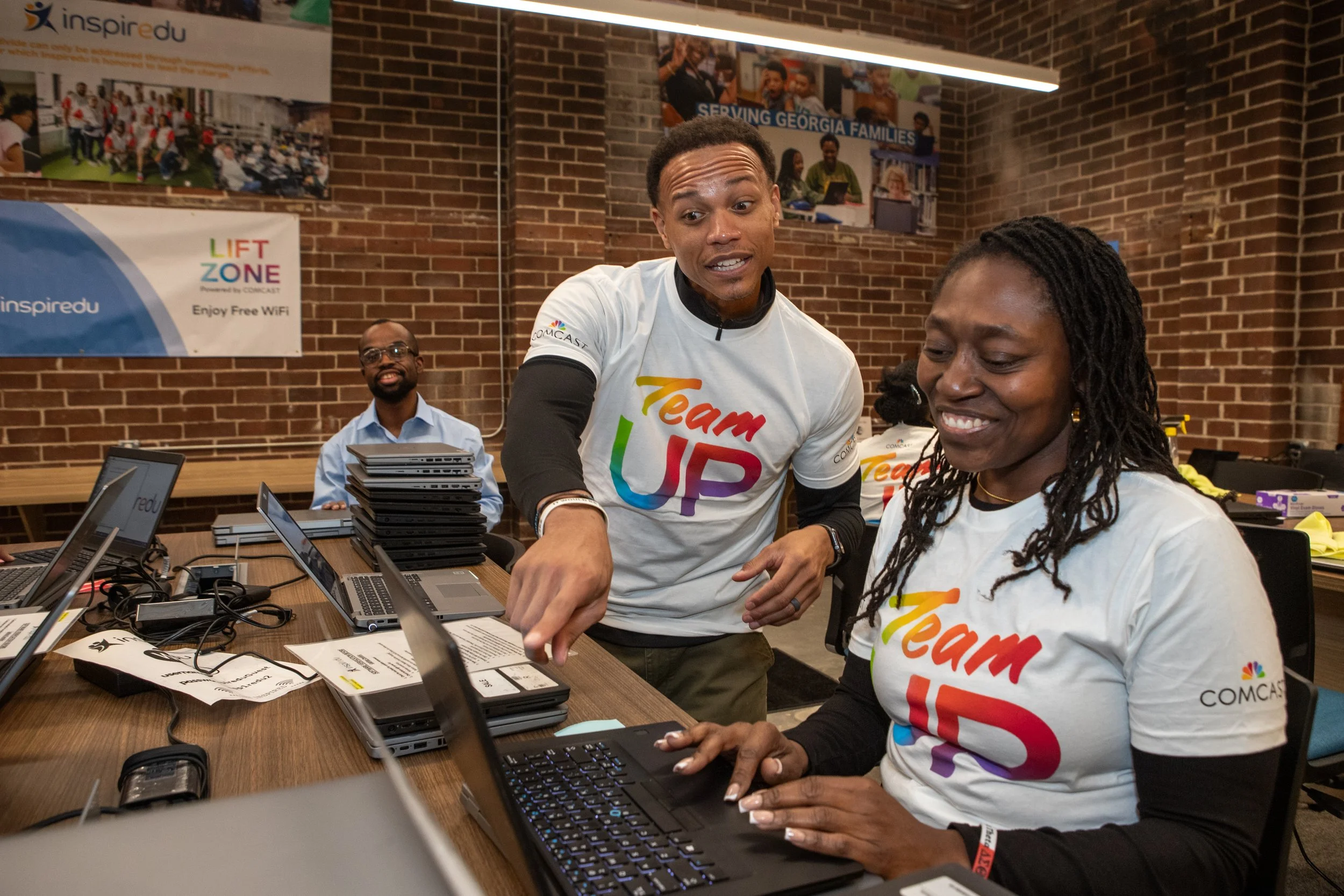 Comcast volunteers assisting with laptops during an Inspiredu digital literacy workshop.