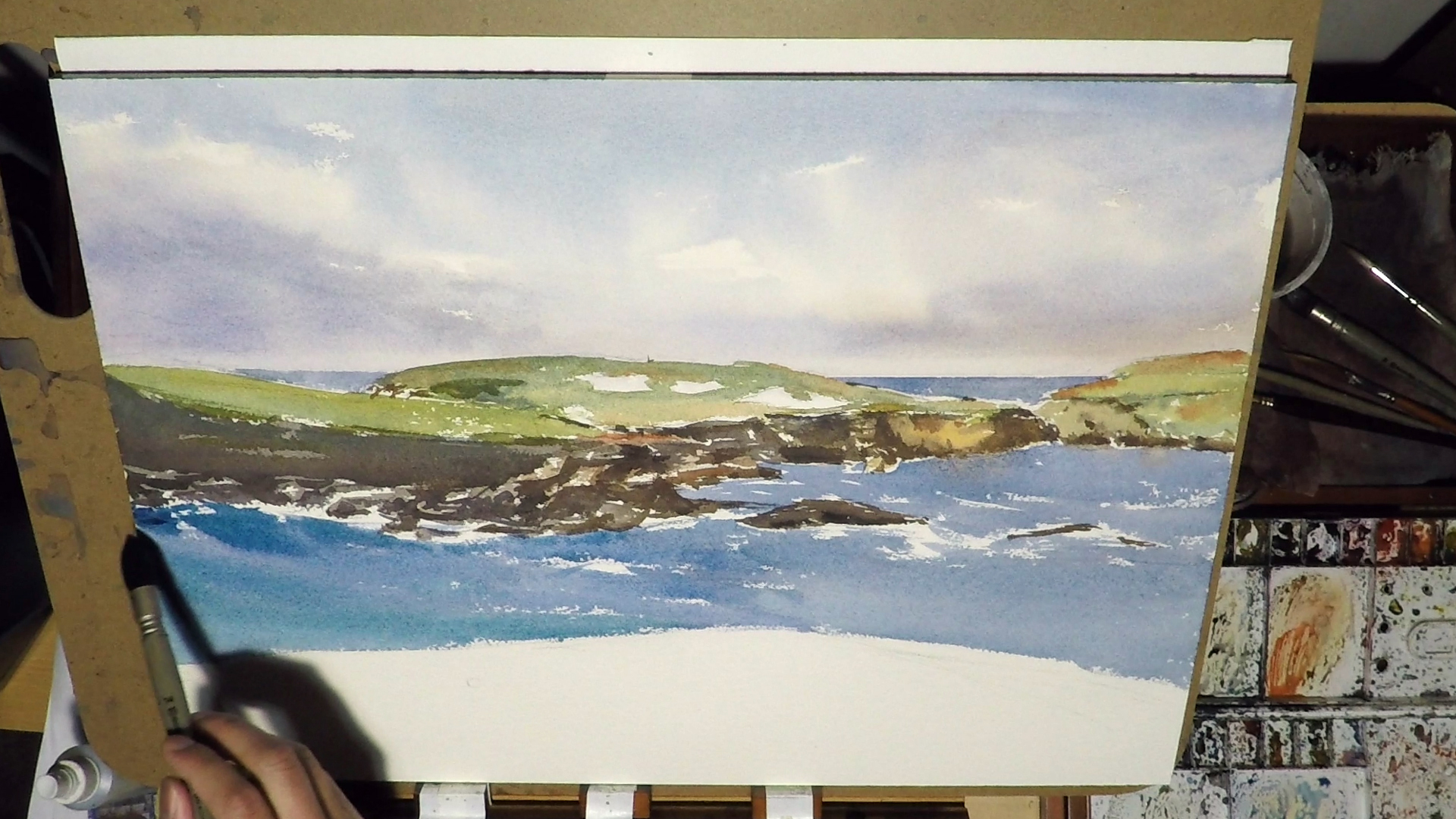 1. Now it's time to do the Ocean. it's really important we do it in one go. I did some fast strokes around the rock to let the dry brush edges becomes the foam and the crashing waves. While the wash is still wet, I added in some quite heavy mixture of Cobalt Turquoise and Cobalt Blue to gives the water some depth. The ocean in the distance typically don't have much reflections, but I added a bit of reflections for the big rock on the right, just to make it a bit more interesting.