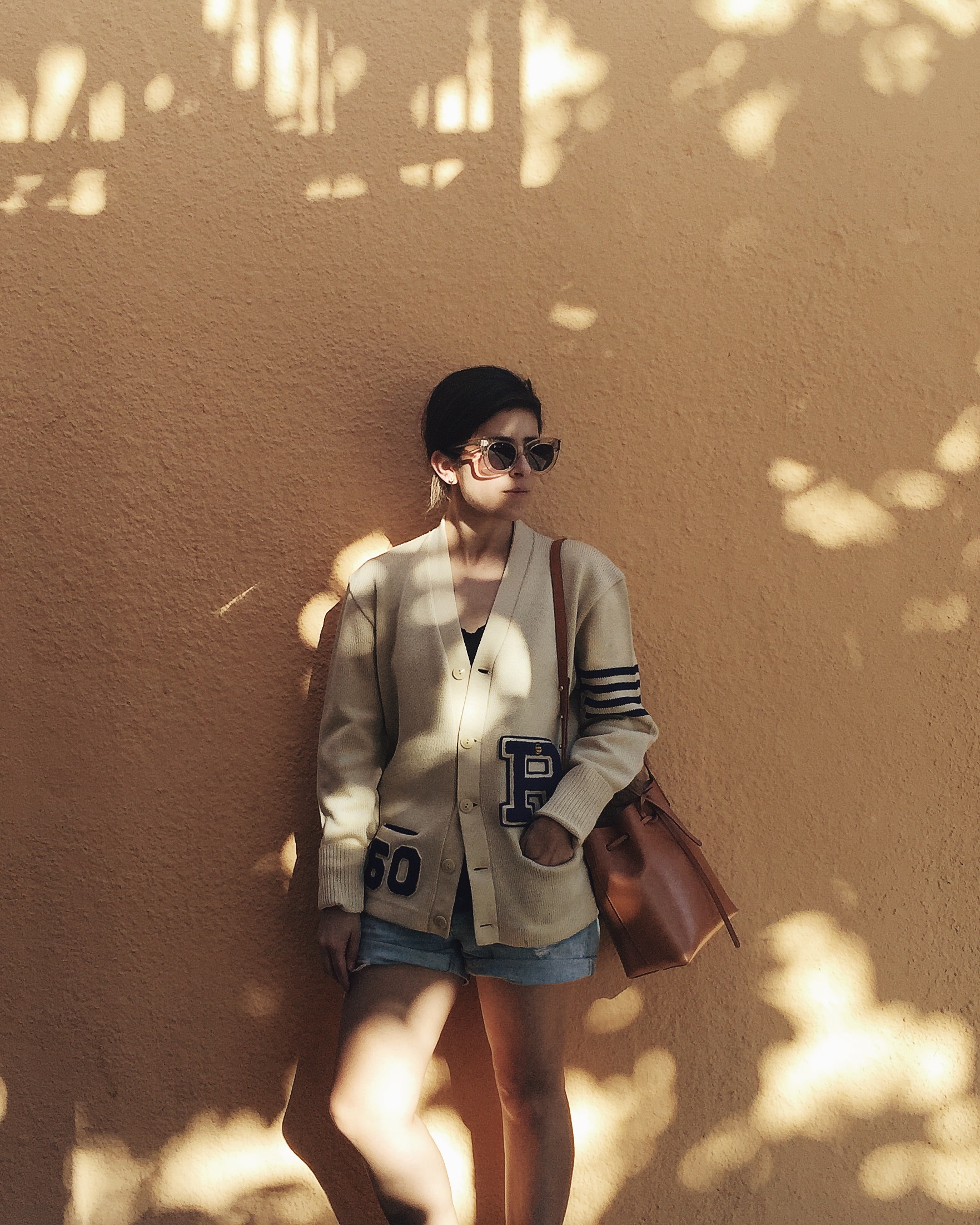 Céline Caty sunglasses in lucite, vintage letterman jacket, Mansur Gavriel mini bucket bag