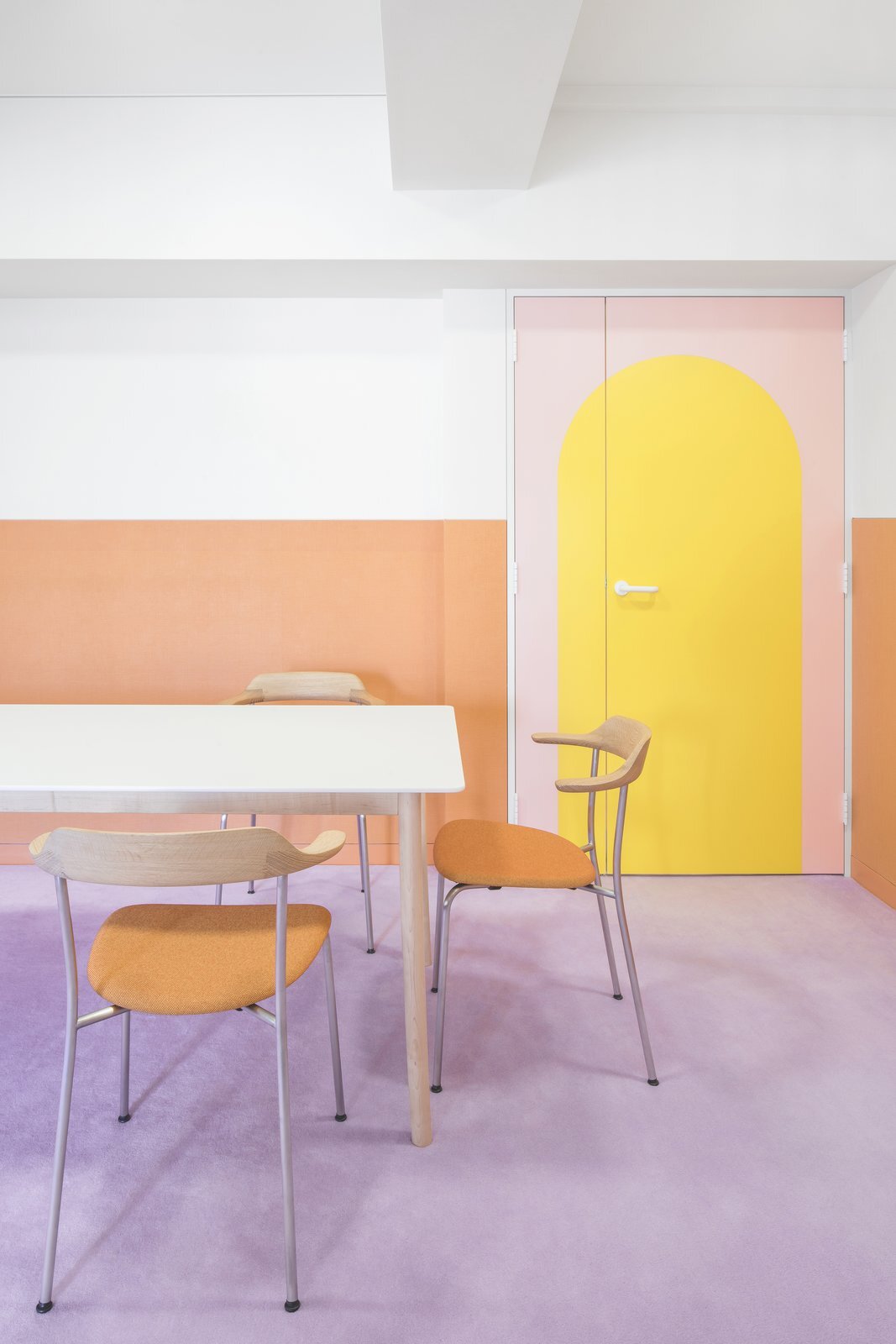 the-pastel-tangerine-chairs-in-the-dining-area-pick-up-the-orange-wainscotting-of-the-walls-and-the-simple-lines-of-the-dining-furniture-allow-the-walls-and-finishes-to-function-as-artwork.jpg