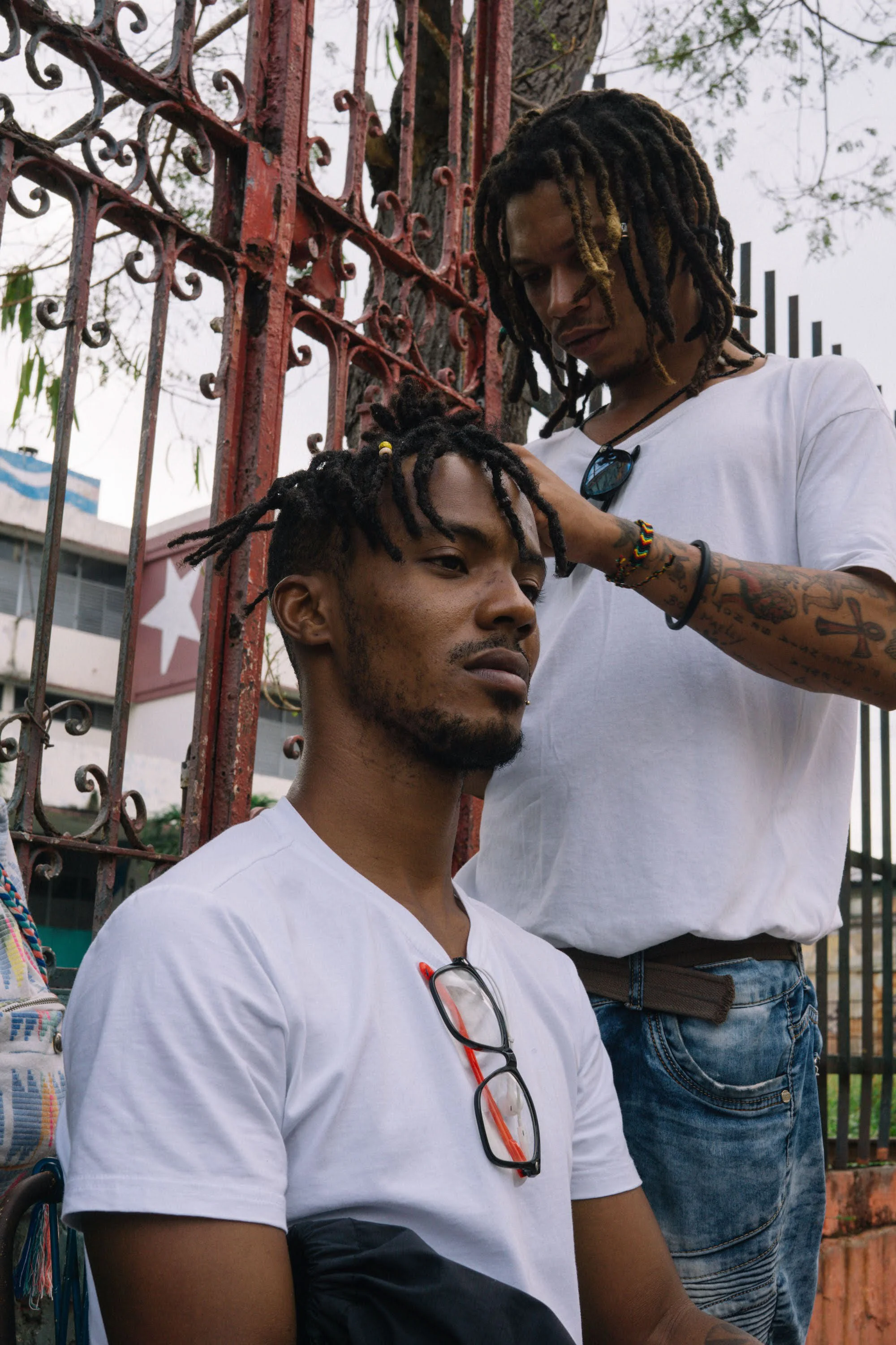two men re-twisting each other’s Locs during a street art festival