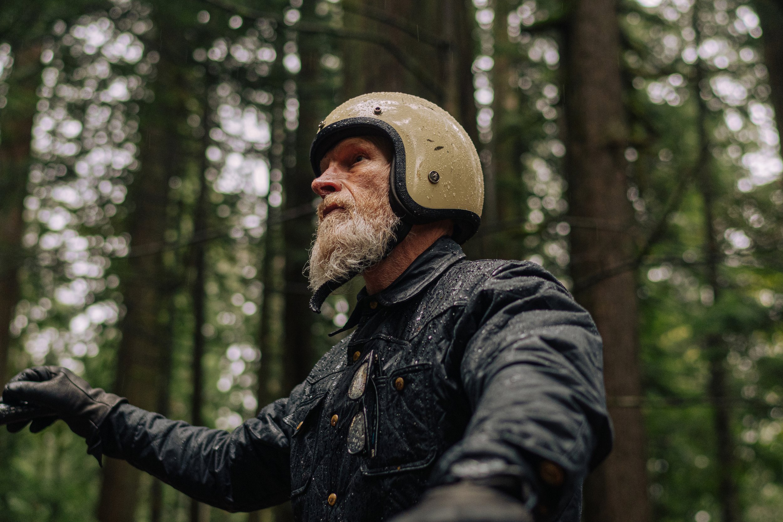 Embracing the elements in style! 🌲🏍️ This rugged adventurer conquers the Pacific Northwest rainforest on his sleek motorcycle, donned in the epitome of cool—the Black Bear Brand wax canvas jacket.