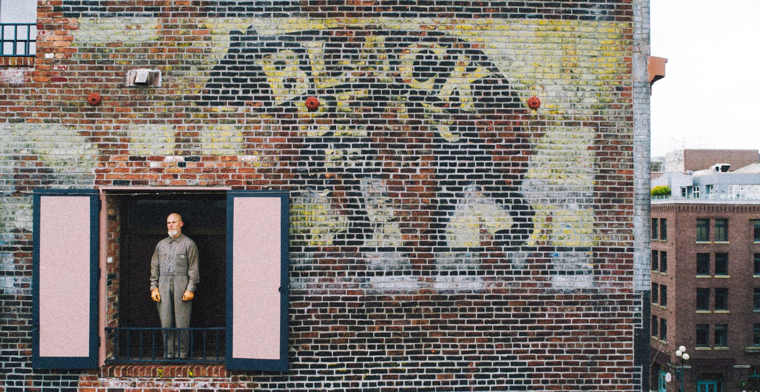Faded painted Black Bear Brand ghost sign on a Seattle brick building with Josh wearing the original Black Bear Brand union 1930 coveralls, color photo.JPG
