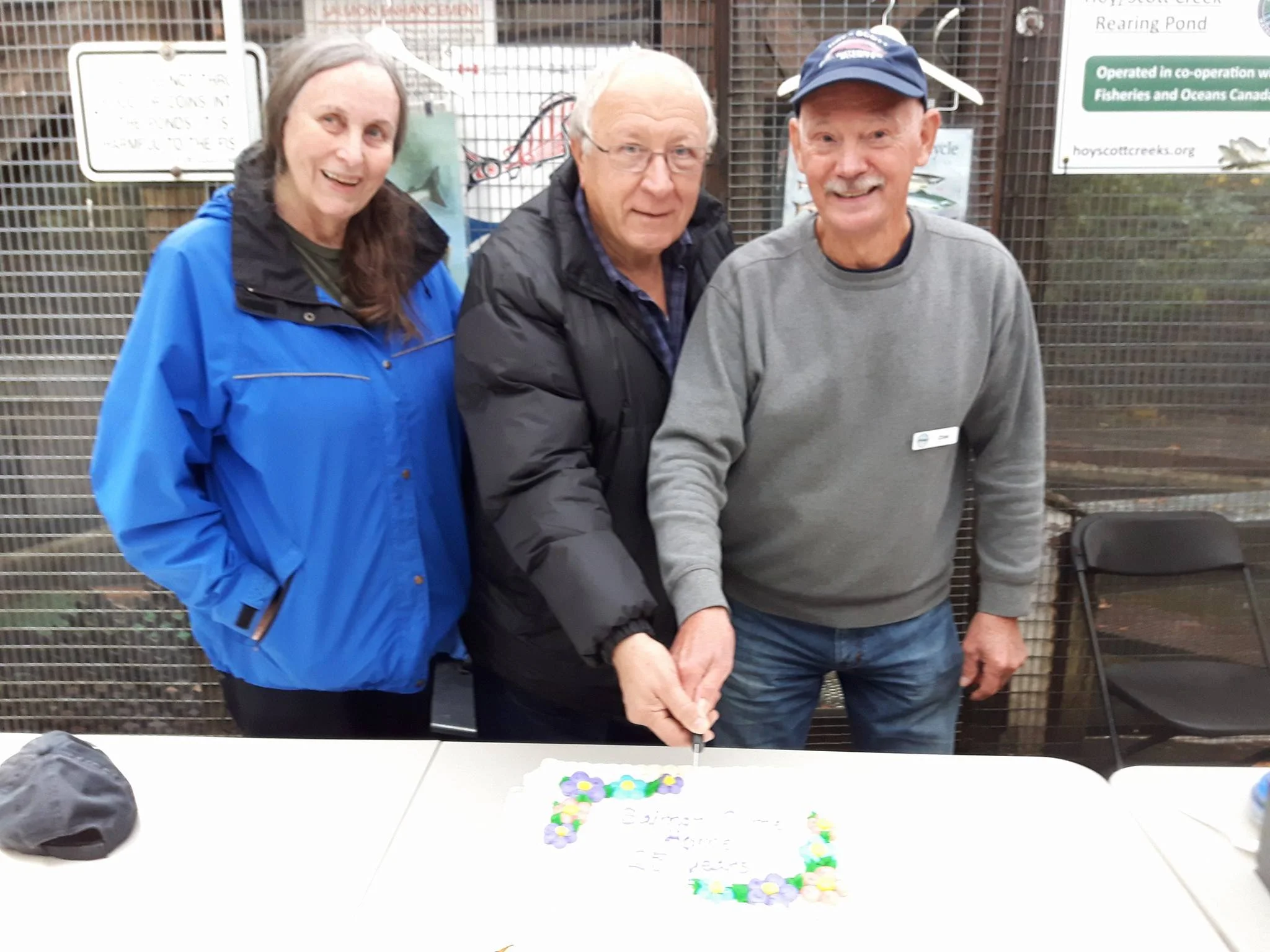 Cutting the cake for 25 years of Salmon Come Home - left to right: Dr. Elaine Golds of Burke Mountain Naturalists who have been coming to Salmon Come Home probably since day 1, Tony Matahlija from North Fraser Salmon Assistance Project, who helped build the hatchery, and HSWS founding member and salmon educator, Chris Hamming.