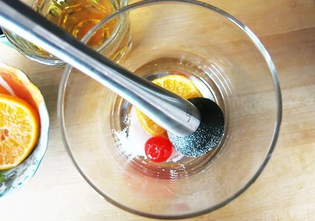 brandy old fashioned muddling the fruit with sugar