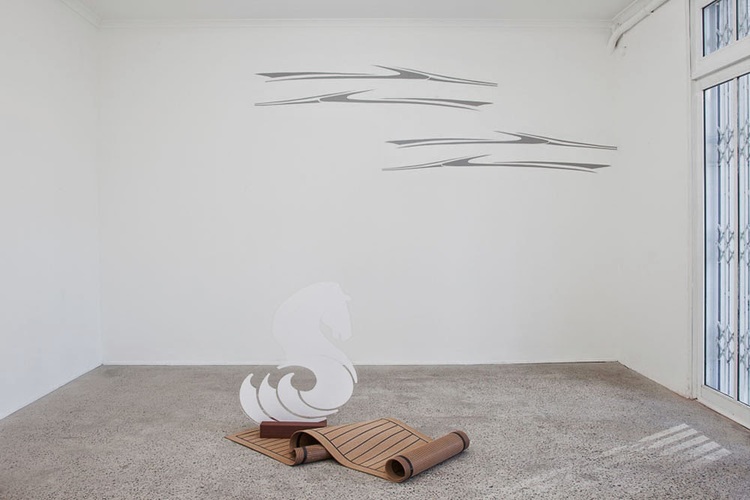 Floor work: Broadening the horizons of your dreams (a discreet sense of luxury) , 2014, laser cut vinyl applied to Perspex, custom made synthetic teak mat, Eco wood decking, 90 x 35 x 14cm. Wall work: Water’s edge , 2014, boat decals painted on wall, 3 x 2 metres.