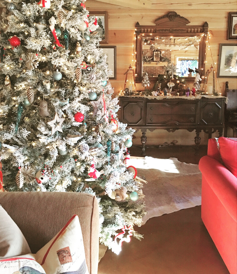 Frosted tree with cabin themed ornaments - antique buffet with cloth manger scene, and framed artwork painted by my late great Aunt.