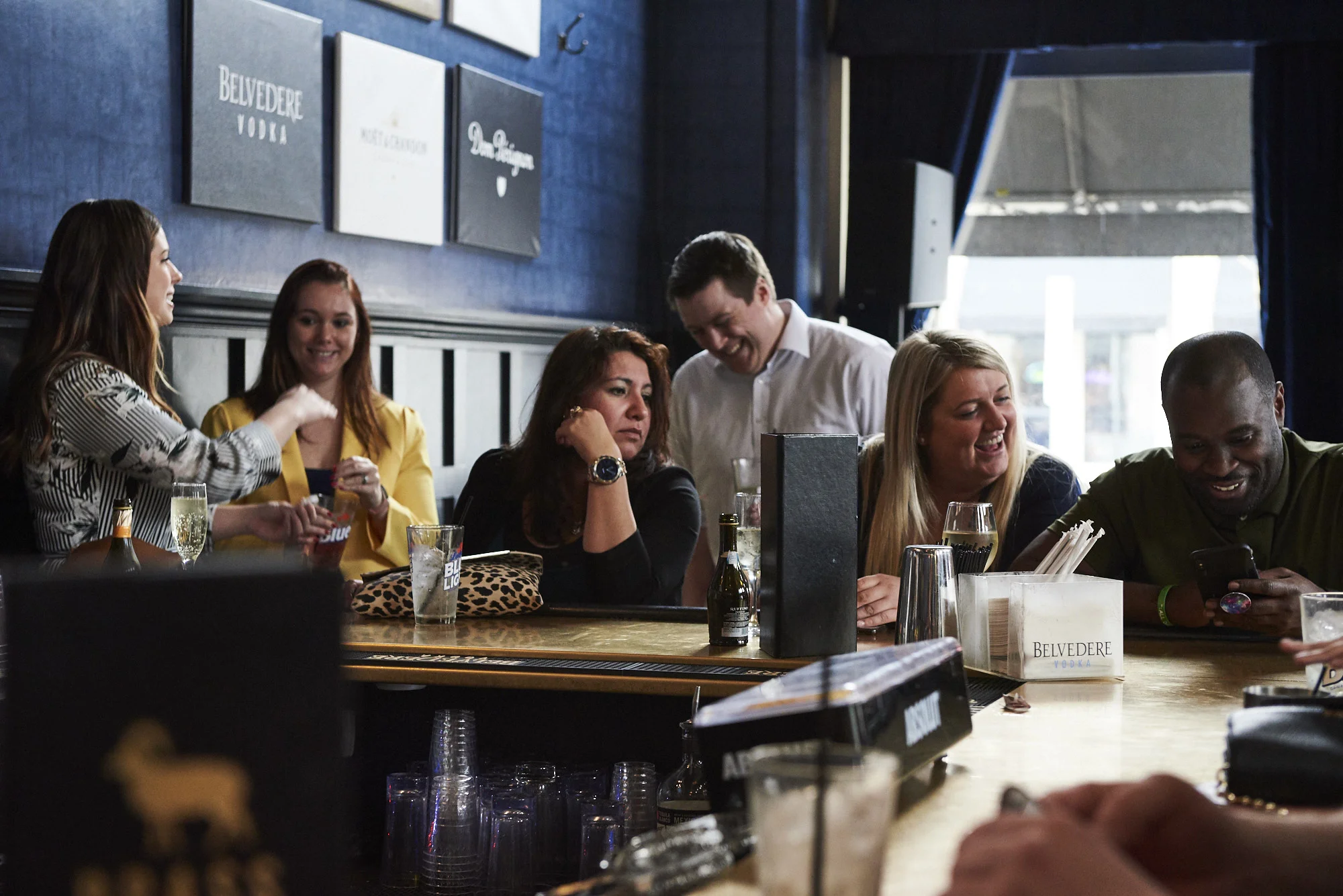 A group of people sitting together at the end of the bar.
