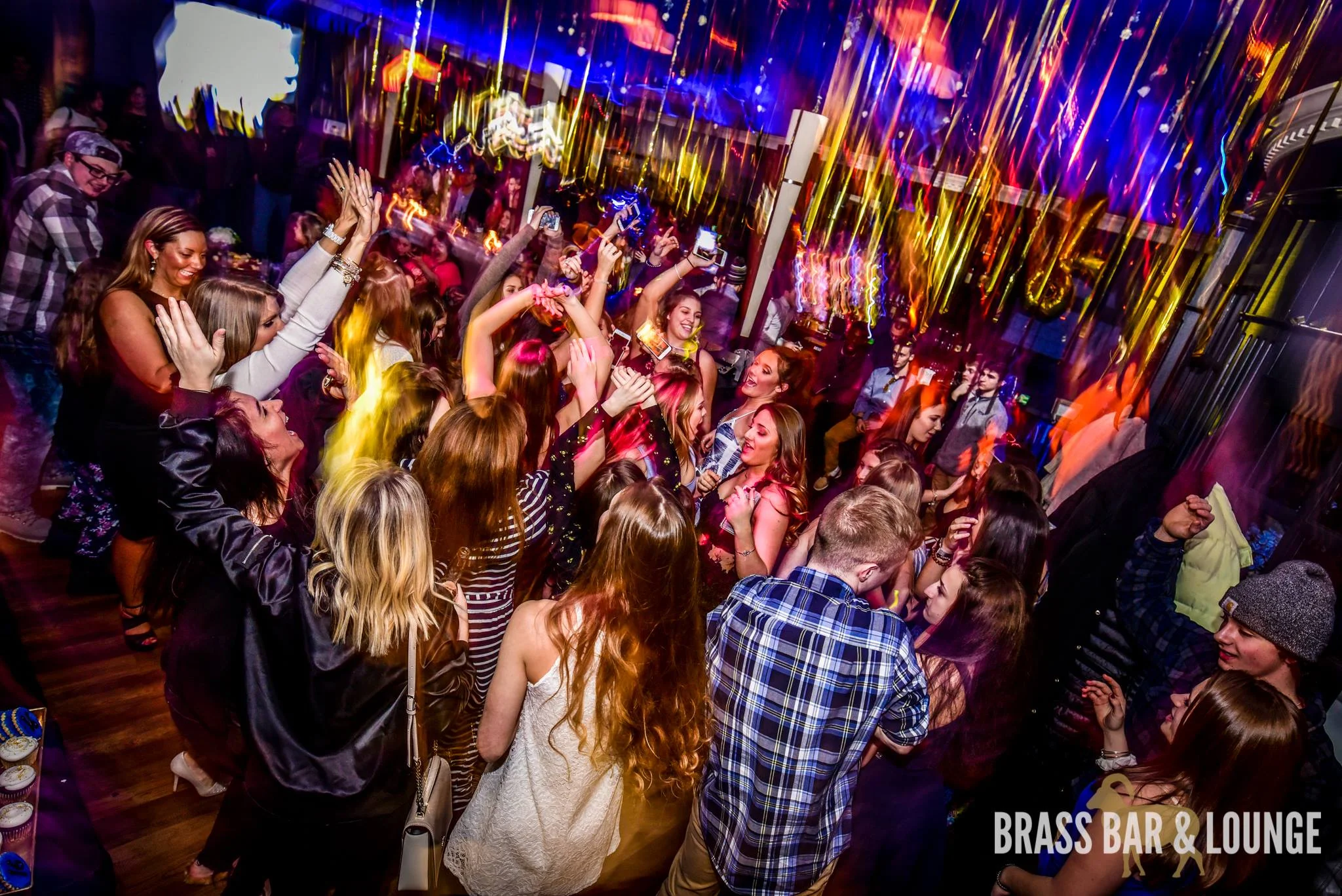 A group of people dancing with gold balloons in the background.