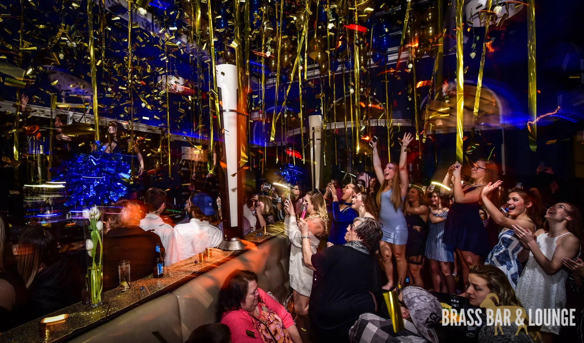 A group of people celebrating as gold confetti comes down.