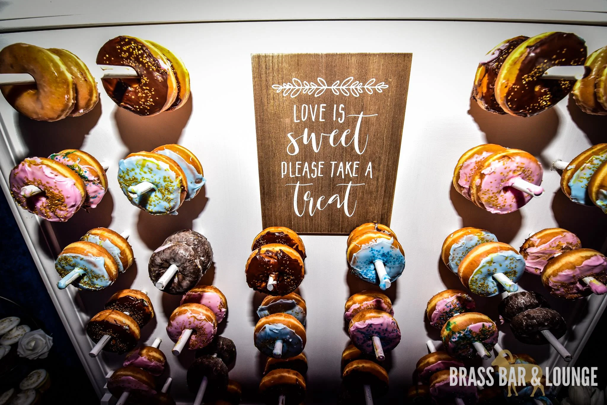 A donut wall with a sign in the middle that reads "Love is sweet, please take a treat."
