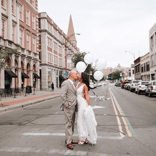 A bride and groom kissing each other in the middle of the street.