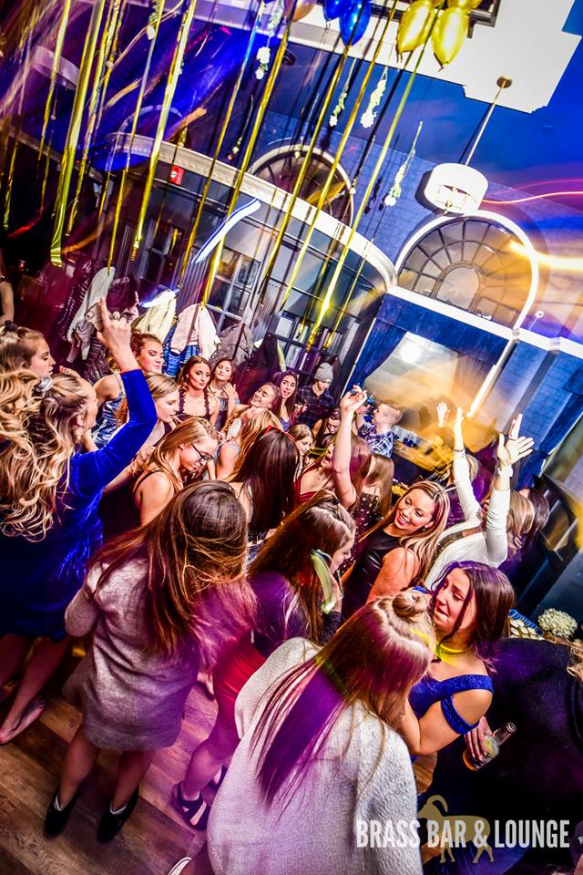A group of girls dancing with balloons above them.