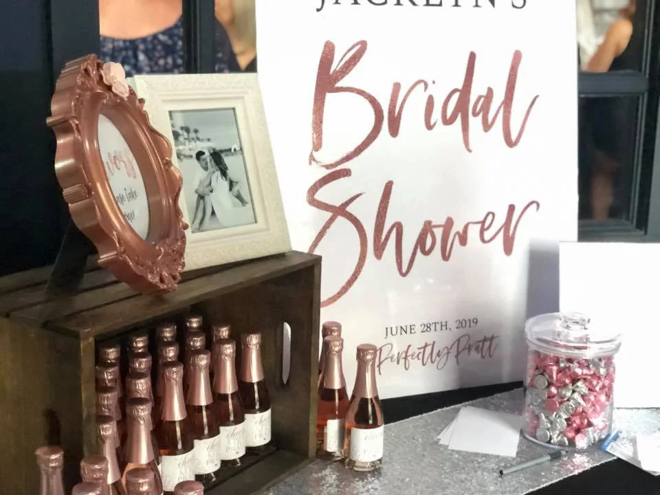 A bridal shower table setup with candy and bottles of rose.