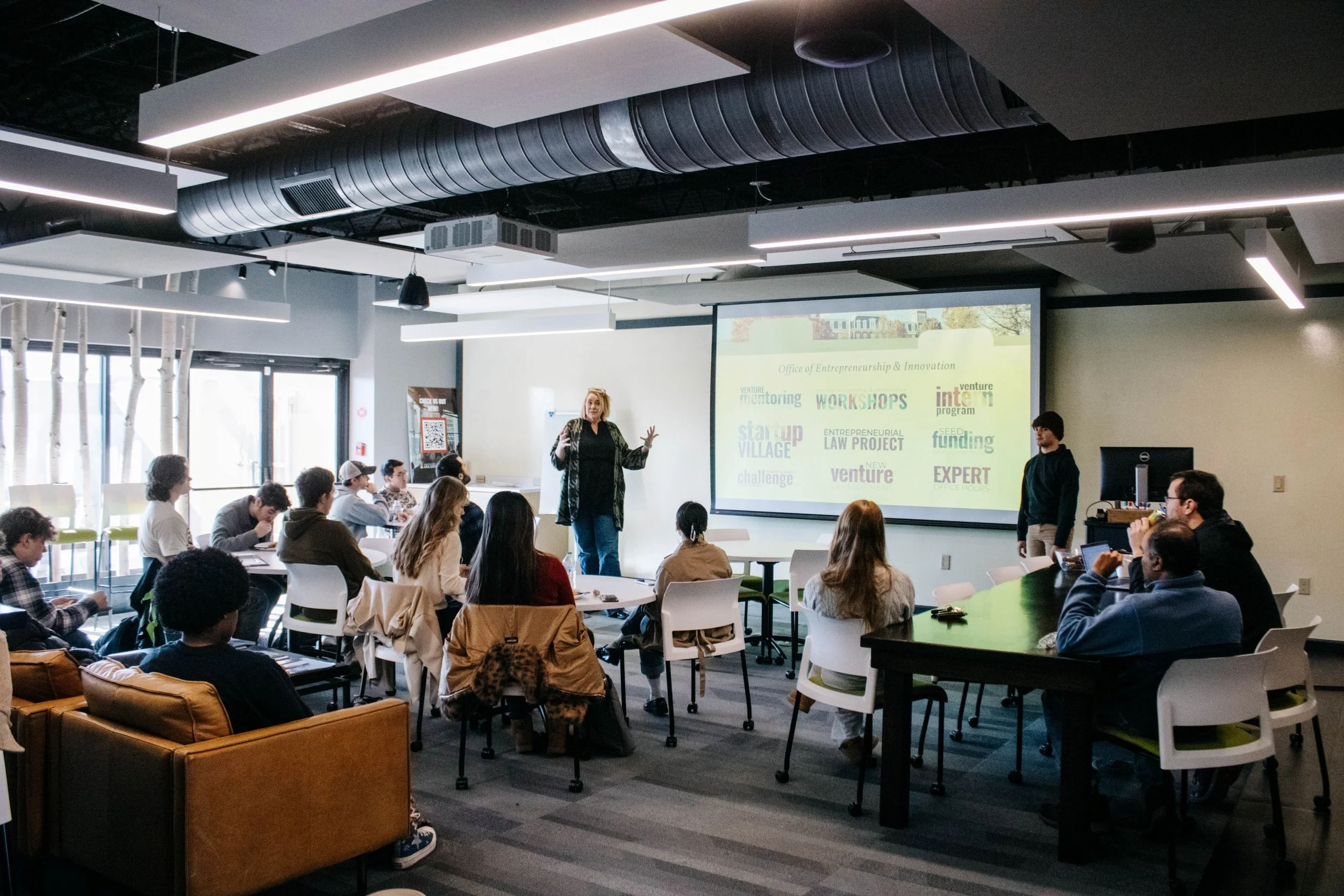 Instructor leads an entrepreneurship and innovation workshop as students gather in a modern classroom.