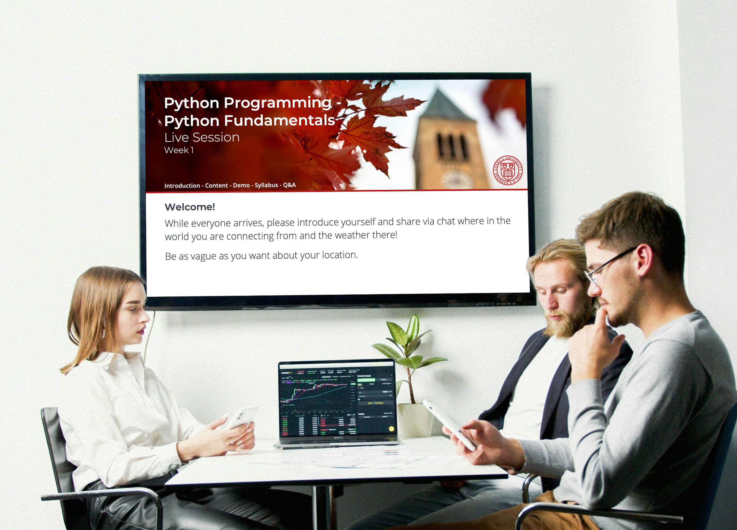 Python programming fundamentals live session displayed on a classroom screen, with students collaborating around a table