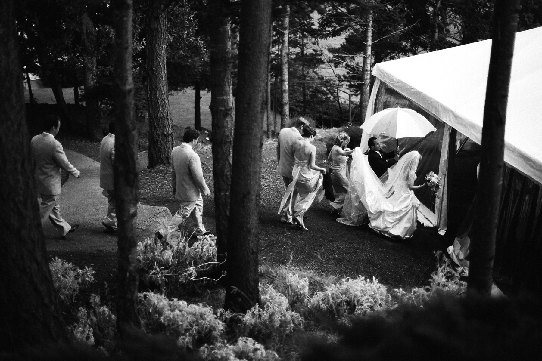Couple and wedding party run to the tent after rain cuts their ceremony short at Rosario Resort on Orcas Island, WA