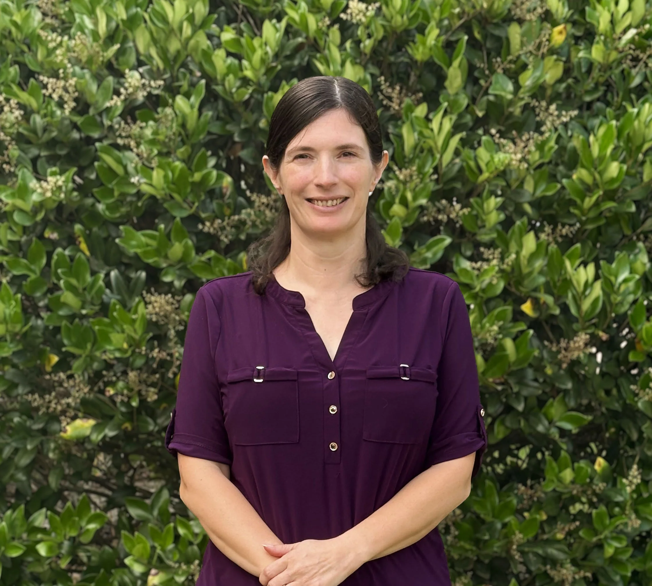 Beach scene at sunset with colorful pink, orange, and purple clouds, ocean waves, and houses on stilts lining the shore.