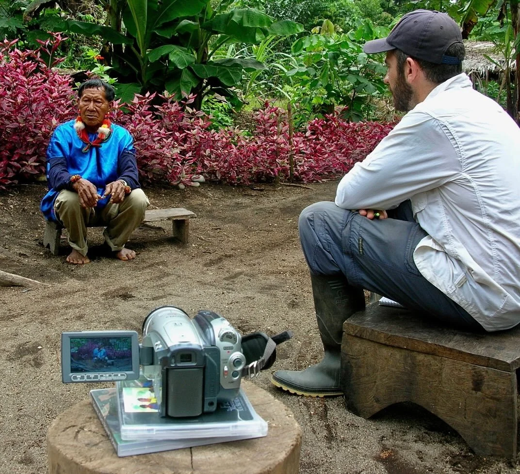 Pictured is anthropologist and President of the Board of the Cofan Survival Fund, Mike Cepek. He is recording an oral history with an elder in the community of Duvuno named Emiliano. Mike was in Duvuno with a team of Cof&aacute;n collaborators workin