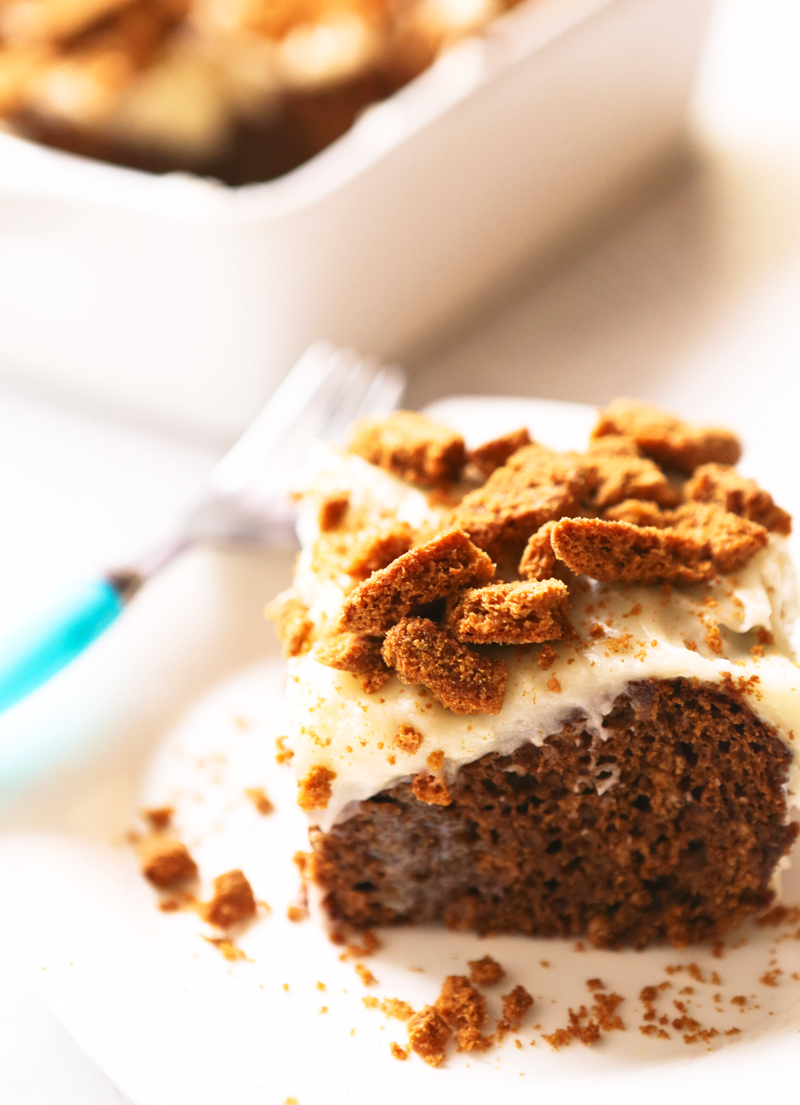 A piece of gingerbread poke cake on a plate, topped with crushed cookies