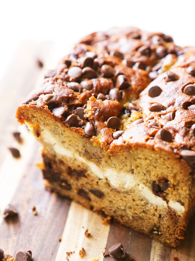 loaf of banana bread cut in half with cream cheese in center and chocolate chips on top