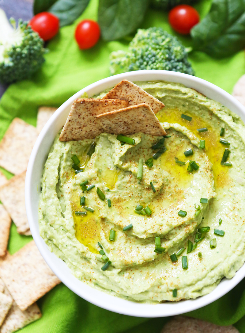 top view of green hummus with crackers stuck into it