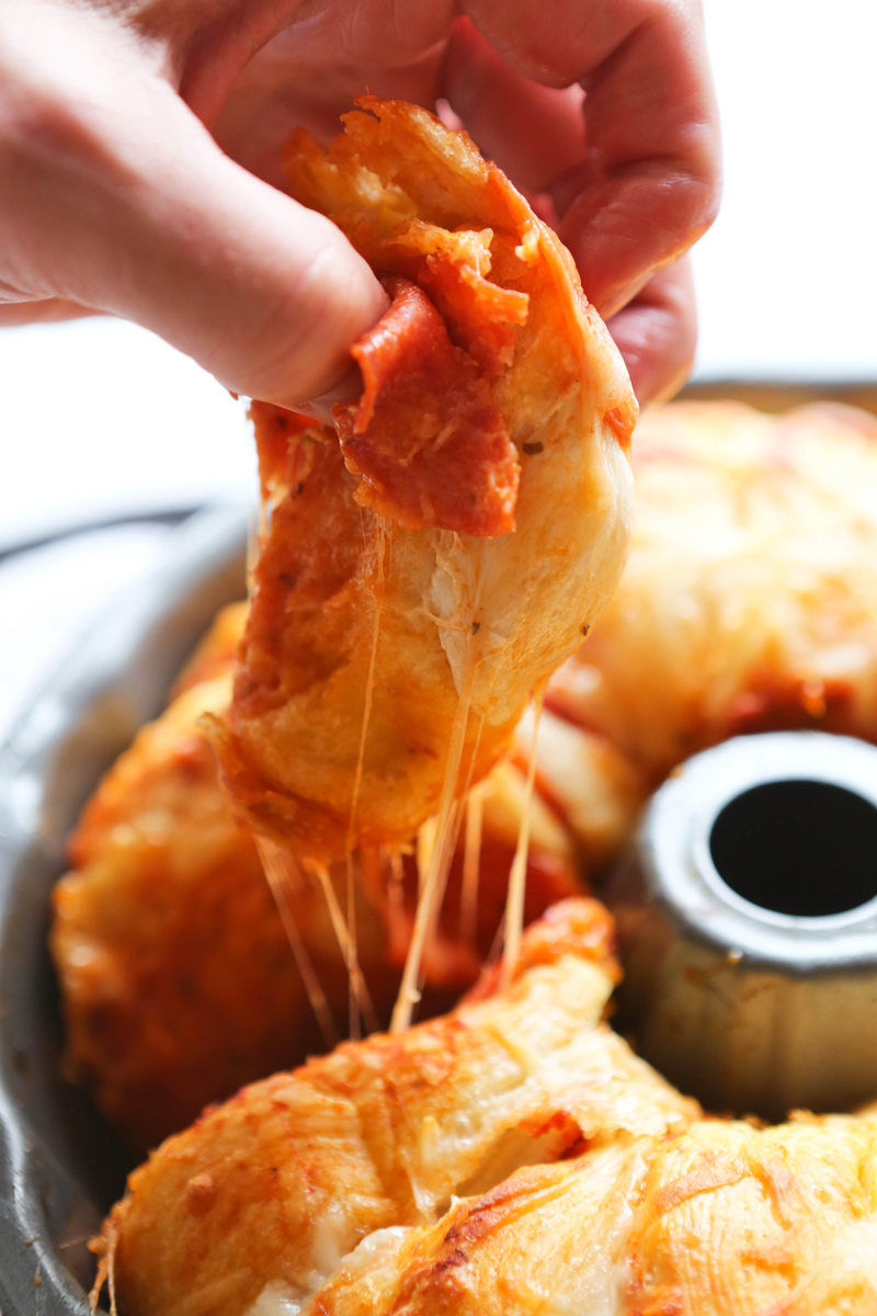 fingers pulling a piece of pizza bread from a pan